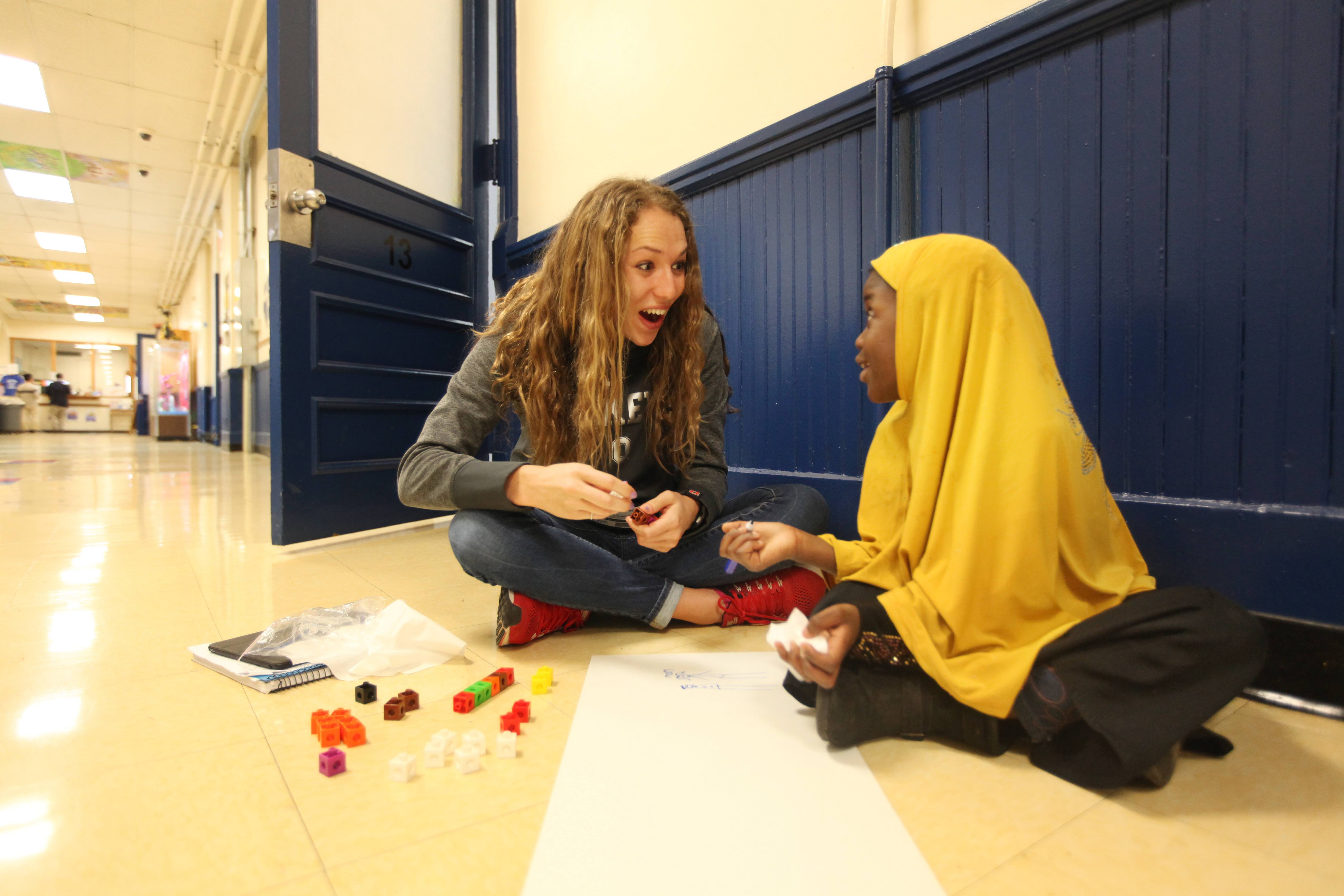 teacher and student sitting in school hallway