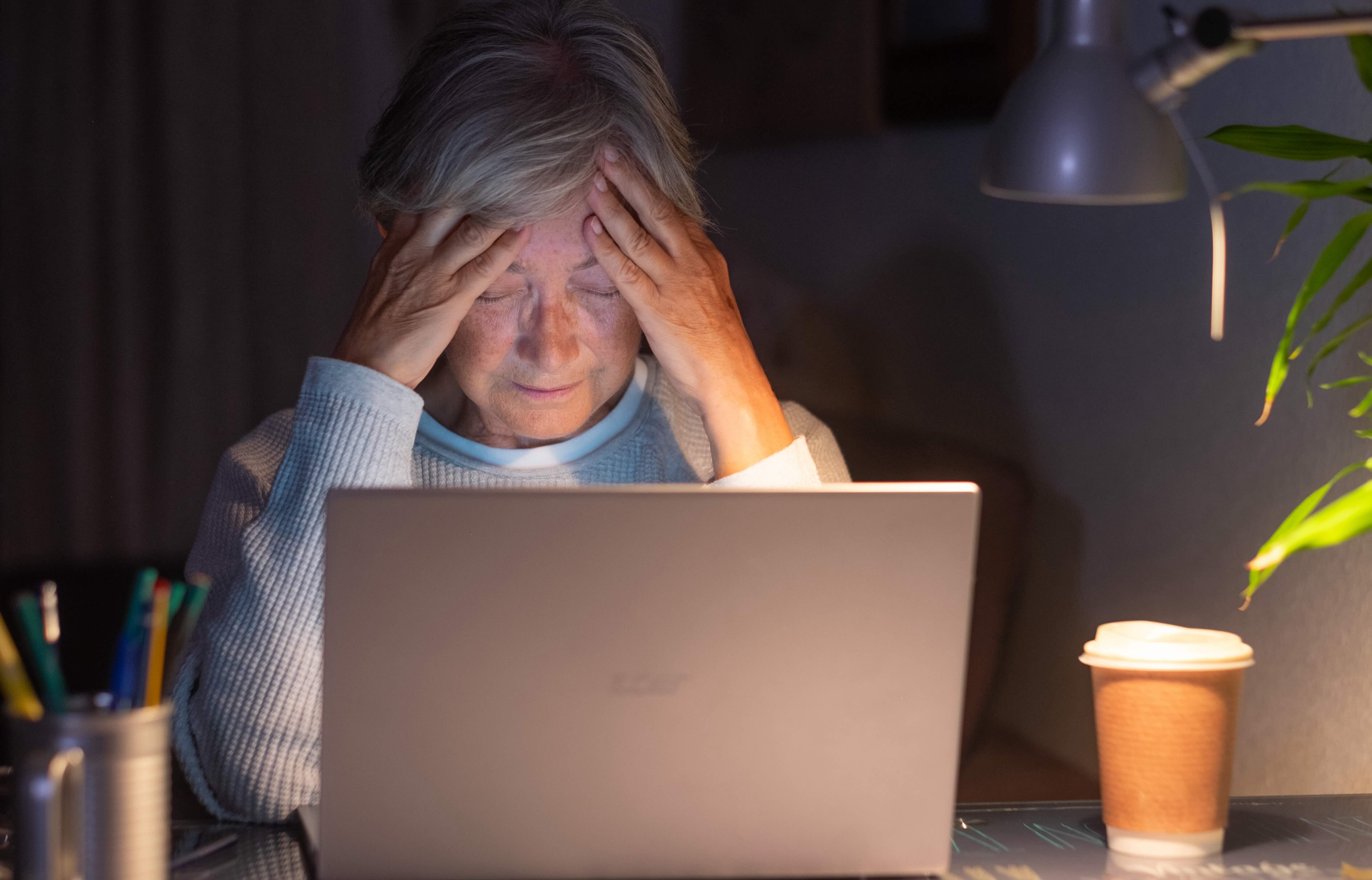 older women alone at her computer looking stressed