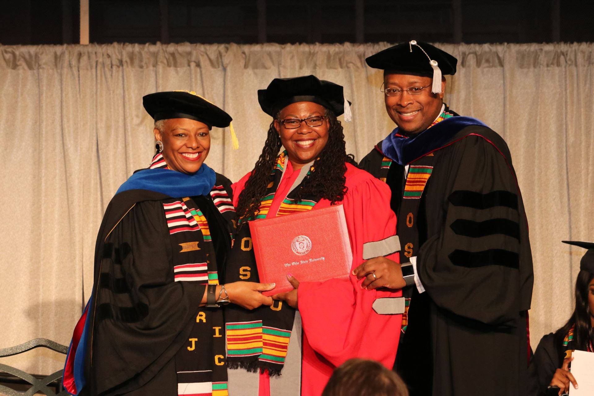 Javaune Adams-Gaston, left, then Ohio State's senior VP of Student Affairs, and James L. Moore III, right, congratulate Moore's advisee Kirsten Smith upon receiving her PhD
