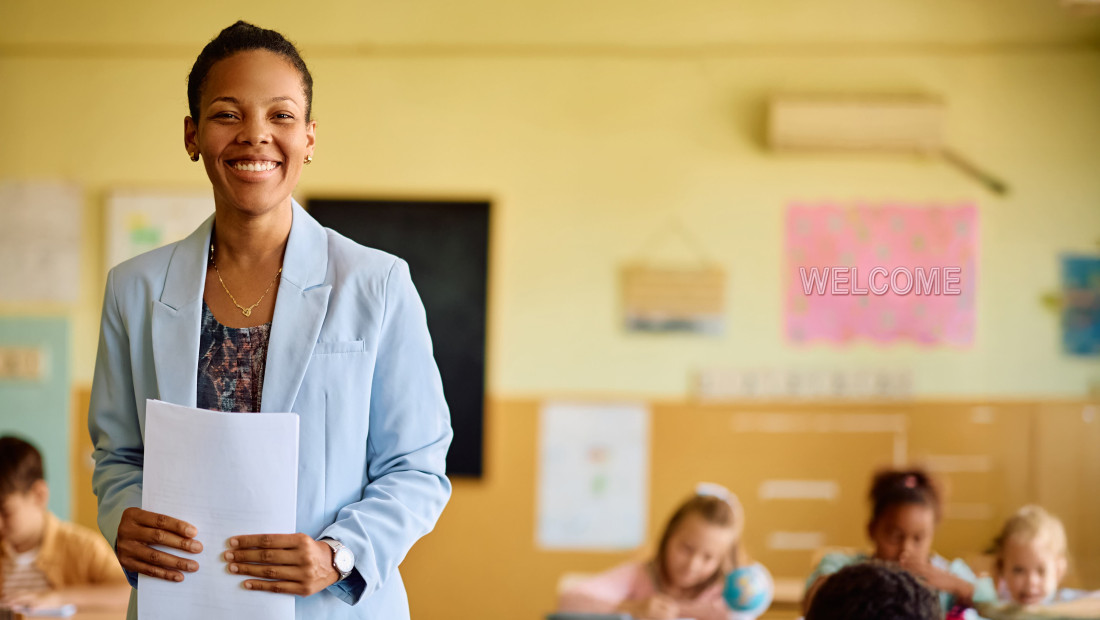 Teacher in front of welcome sign