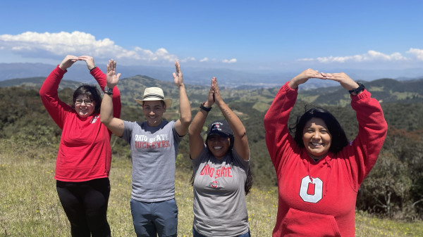 Students wearing Ohio State shirts using their arms to spell O-H-I-O while on a hike