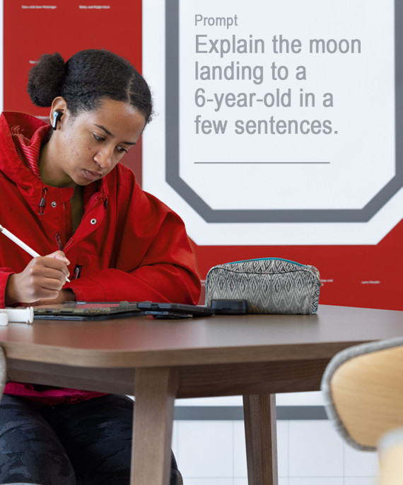 Ohio State student sitting at a desk in front of a large block "O" sign