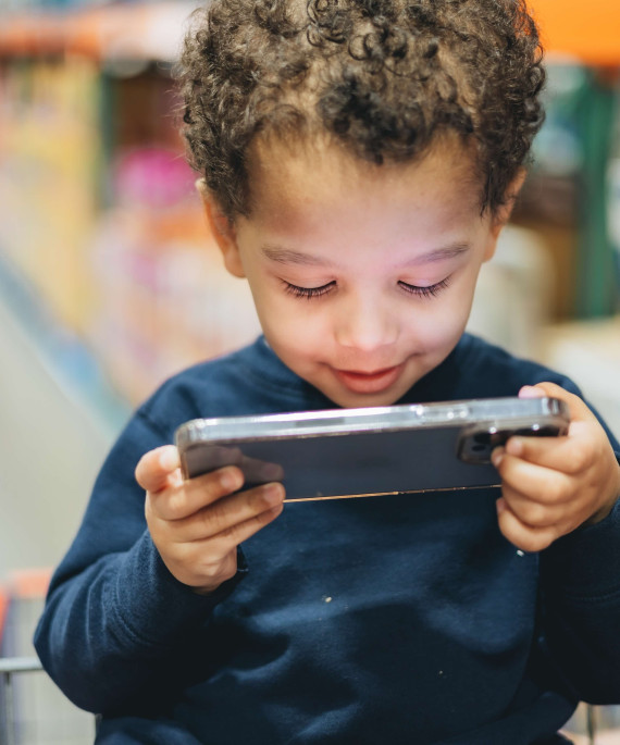 Young child in shopping cart looking at a phone