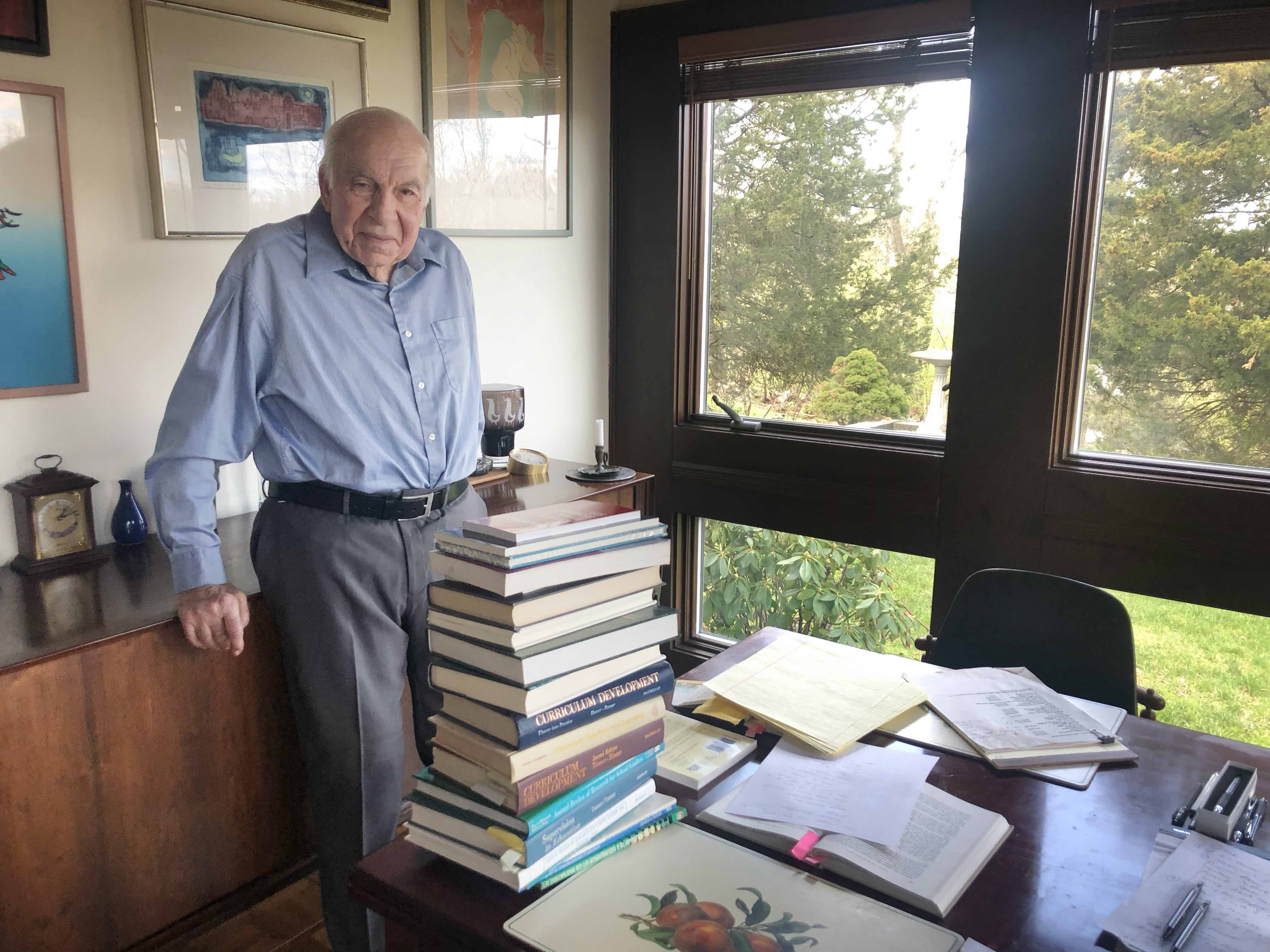 Daniel Tanner leaning with a stack of books