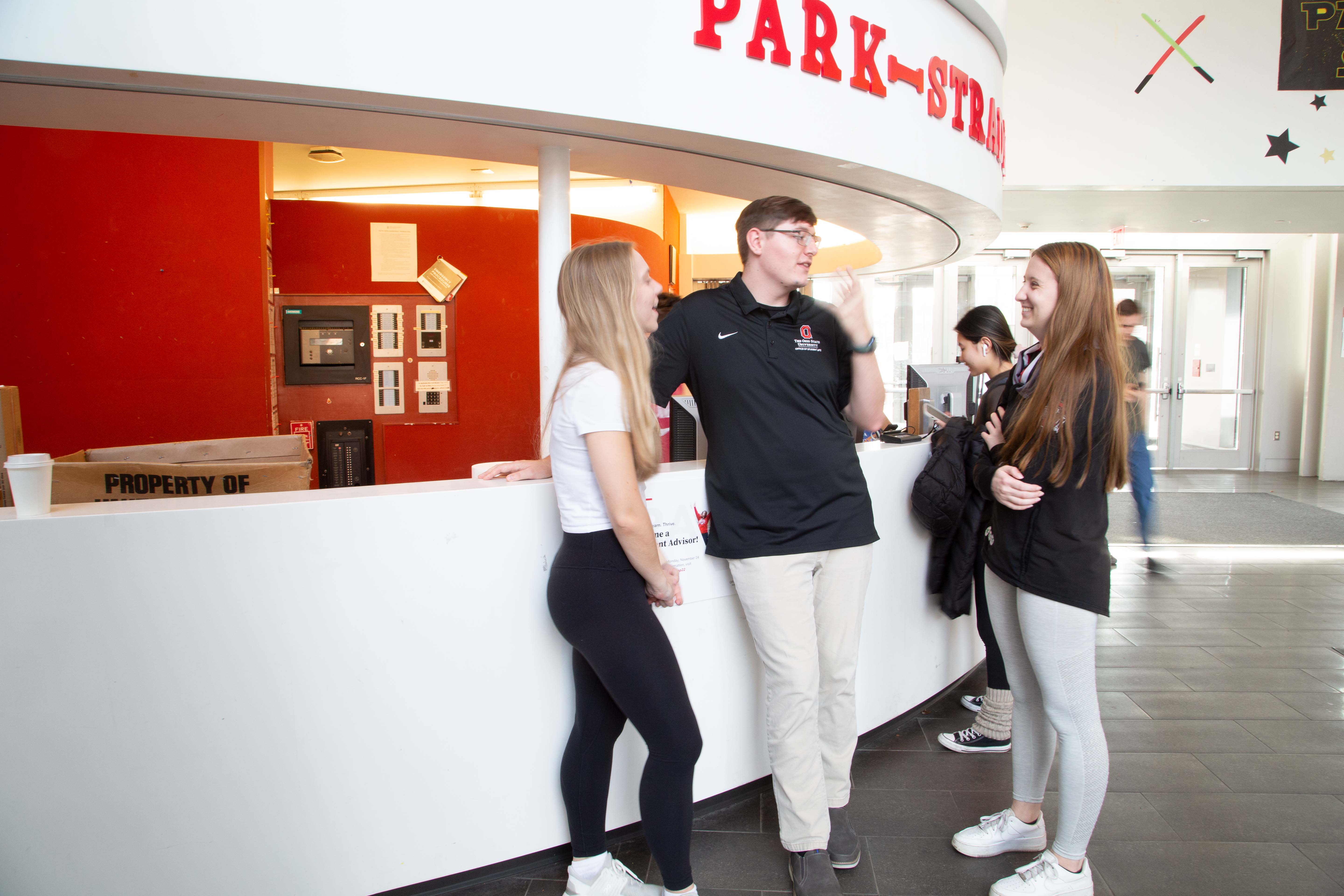 Ohio State students talking at the front desk of a building